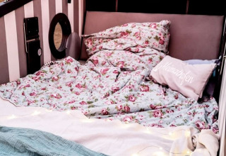 Cozy glamping accommodation in Kiel with floral bedding and pillows inside a beach chair on the fjord.