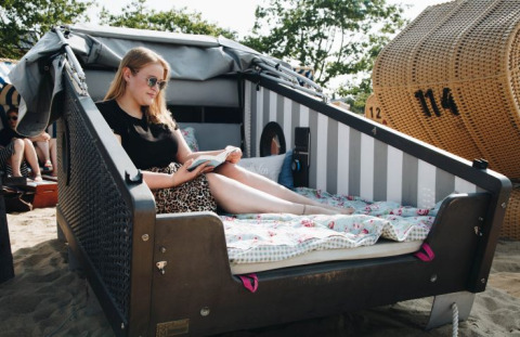 Vrouw geniet en leest in een Strandmand-glampingsuite aan het strand bij de Kieler Fjord, Kiel Sailing City.