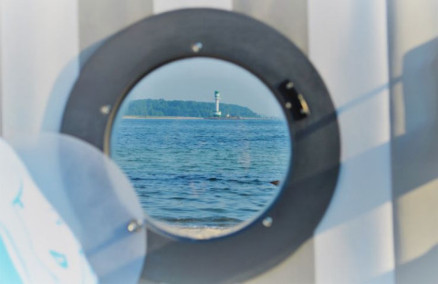 Blick aus dem Glamping 'Kiel Sailing City - Strandmand' auf den Kieler Fjord mit Leuchtturm.