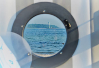Blick aus dem Glamping 'Kiel Sailing City - Strandmand' auf den Kieler Fjord mit Leuchtturm.