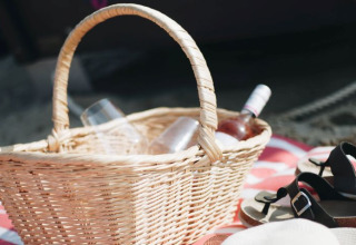 Picnic basket with wine and glasses on a blanket, ideal for glamping at Kiel Sailing City - Strandmand.