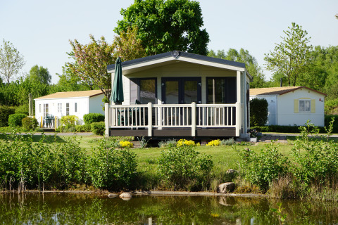 Chalets de luxe au bord d’un lac au Camping Südsee-Camp, avec terrasse et verdure en Basse-Saxe.