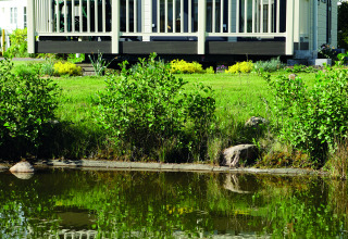 Luxe glamping chalet aan een vijver bij Camping Südsee-Camp, omringd door groene natuur en rust.