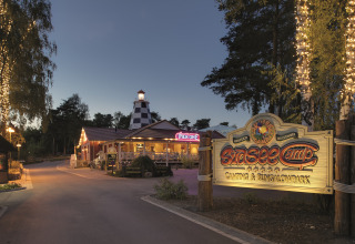Entrada al camping Südsee-Camp y bungalow park al anochecer con luces brillantes y señal iluminada.