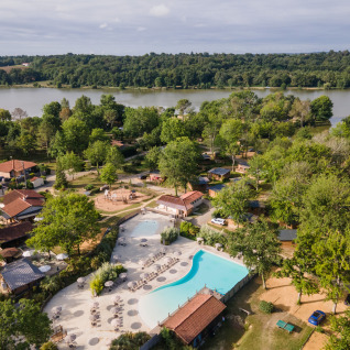 Luftaufnahme von Camping Huttopia Lac de l'Uby - Glamping Occitanie mit Pool, See und grüner Landschaft.