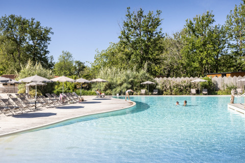 Piscina exterior con tumbonas y sombrillas en Camping Huttopia Lac de l'Uby - Glamping Occitanie.