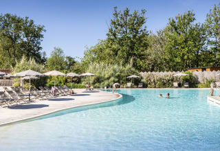 Udendørs swimmingpool med liggestole og parasoller på Camping Huttopia Lac de l'Uby - Glamping Occitanie.
