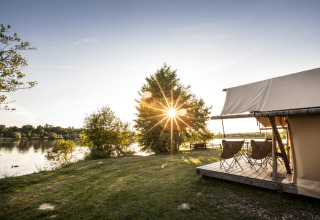 Sonnenuntergang am See bei Camping Huttopia Lac de l'Uby - Glamping Occitanie, mit Zelt und Stühlen.
