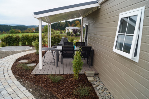 Patio coperto con sedie e tavolo all’esterno di uno chalet al Camping en Vakantiepark Brilon, Renania Settentrionale-Vestfalia.