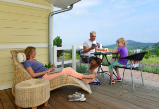 Famille se détend sur la véranda de Camping en Vakantiepark Brilon - Chalets Noordrijn-Westfalen, expérience glamping.