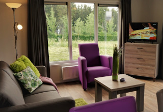 Interni di un alloggio glamping nel Camping en Vakantiepark Brilon, Chalets Nord Reno-Westfalia, con poltrone viola.