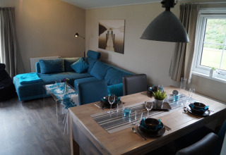 Espace salon et salle à manger moderne en chalet glamping au Camping en Vakantiepark Brilon, canapé bleu.