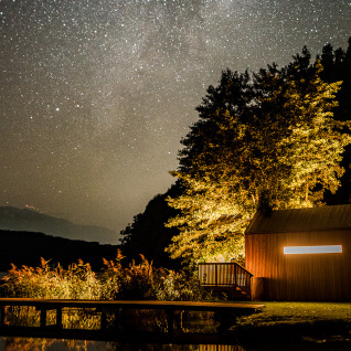 Glamping accommodatie Biwak onder de Sterren in Oostenrijk, sfeervolle hut bij een meer onder fonkelende sterren.