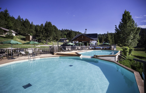 Piscina all'aperto presso Huttopia Font-Romeu - Glamping Languedoc-Roussillon, circondata da alberi e sdraio.