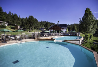 Outdoor swimming pool at Huttopia Font-Romeu - Glamping Languedoc-Roussillon, surrounded by trees and loungers.