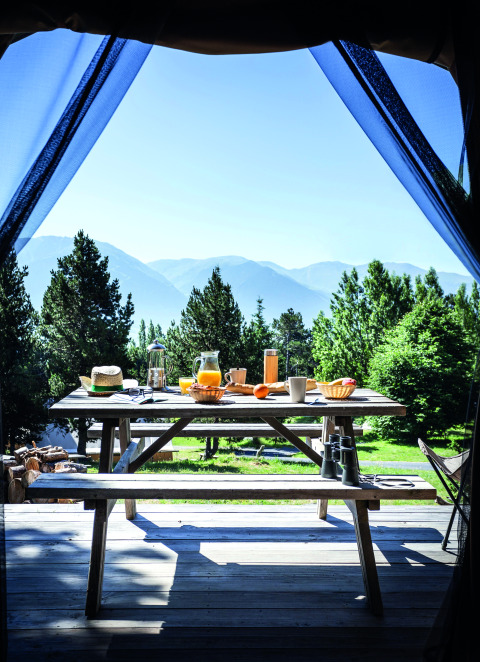 Uitzicht vanuit een glamping tent op een ontbijttafel bij Huttopia Font-Romeu, Languedoc-Roussillon.
