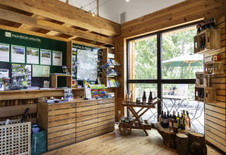 Innenansicht des Infozentrums von Huttopia Font-Romeu - Glamping Languedoc-Roussillon mit Broschüren und Wein.