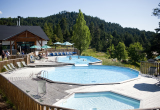Outdoor pools and sun loungers at Huttopia Font-Romeu glamping site in Languedoc-Roussillon, surrounded by forest.