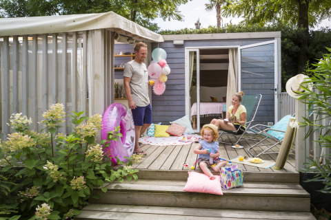 Family enjoys a relaxed summer day on terrace at Vallicella Glamping Resort - Cottages Toscane with decorations.