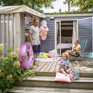 Family enjoys a relaxed summer day on terrace at Vallicella Glamping Resort - Cottages Toscane with decorations.