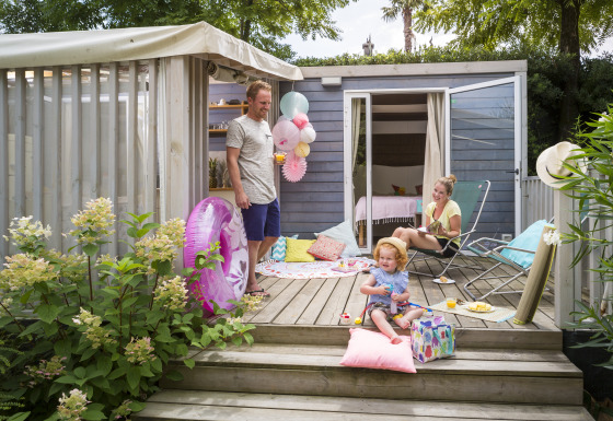 Famiglia si gode una giornata estiva sulla terrazza al Vallicella Glamping Resort - Cottages Toscane, immersa nel verde.