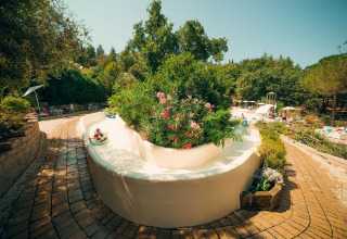 Vandland og vandrutsjebane omgivet af smukke grønne planter på Vallicella Glamping Resort i Toscana.