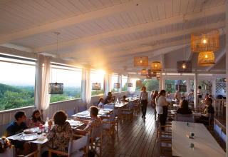 Solrig restaurant med træloft og panoramaudsigt, gæster nyder middag på Vallicella Glamping Resort.