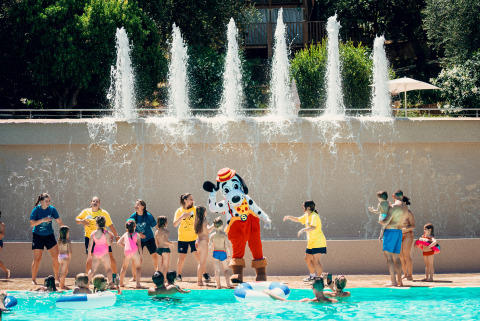 Kids and adults play by the pool with a mascot at Vacanze col Cuore: Vallicella Glamping Resort in Tuscany.