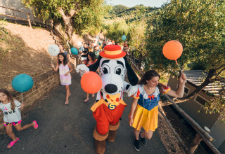 Bambini e adulti festeggiano con palloncini al Vallicella Glamping Resort - Cottages Toscane durante una parata festiva.