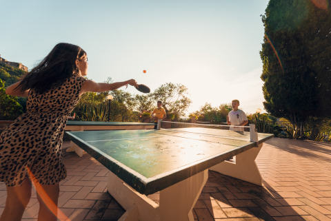 Jugendliche spielen Tischtennis im Freien im Vallicella Glamping Resort in der Toskana, umgeben von Natur.