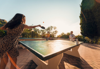 Young people playing outdoor table tennis at Vallicella Glamping Resort in Tuscany, surrounded by nature and sun.