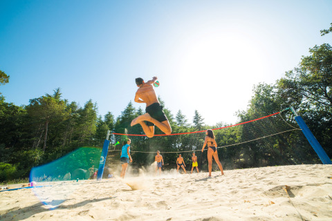Gasten spelen beachvolleybal in de zon bij Vallicella Glamping Resort, omgeven door Toscaans landschap.