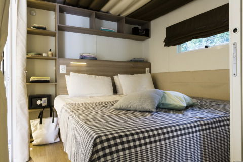 Knusse glampingaccommodatie bij Vallicella Glamping Resort met bijzonder bed, open planken en veel licht.