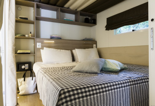 Cozy glamping accommodation at Vallicella Glamping Resort with a stylish bed, shelving, and natural light.