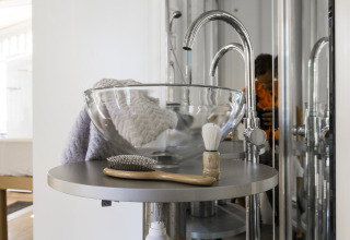 Baño moderno de glamping con lavabo de cristal, cepillo y brocha de afeitar en Vallicella Glamping Resort Toscana.