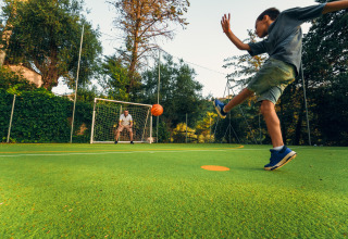 Junge schießt einen Ball aufs Tor, während ein Erwachsener im Tor steht bei Vallicella Glamping Resort.