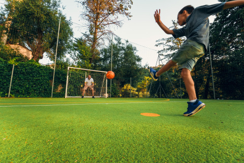 Kind schopt een bal richting het doel met een volwassene als keeper bij Vallicella Glamping Resort, Toscane.