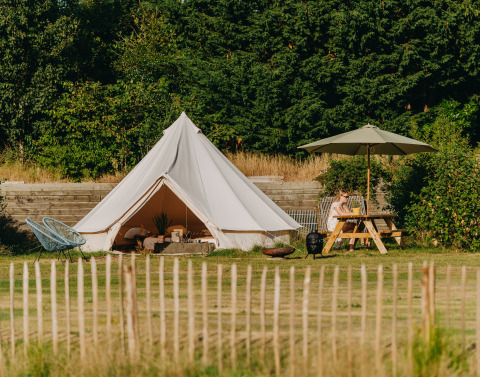 Glamping accommodatie met REBL Outdoor Bell tent in Friesland, Nederland, met picknicktafel en parasol.