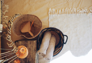 Ambiance chaleureuse chez REBL Outdoor – Bell tenten Friesland, avec paniers, serviettes et déco naturelle.