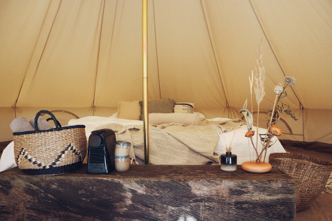 Binnenkant van een REBL Outdoor Bell tent in Friesland met gezellig bed, manden en natuurlijke decoratie.
