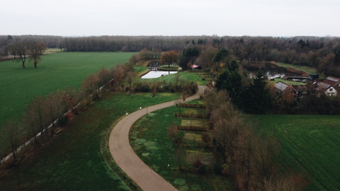 Aerial view of REBL Outdoor – Bell tenten Friesland glamping site with tents, pond, and lush green fields.