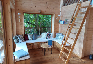 Gezellige zithoek in Sankt Martin boomhut in Rijnland-Palts, omringd door houten muren en kussens.