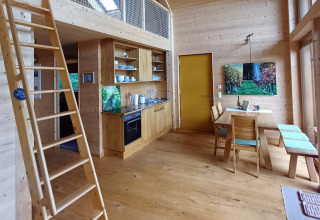 Vista interior de la Sankt Martin boomhut, alojamiento glamping de madera con cocina y comedor modernos.