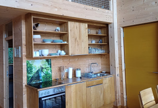 Cuisine moderne en bois dans l’hébergement glamping Sankt Martin boomhut, Boomhutten Rijnland-Palts, Allemagne.