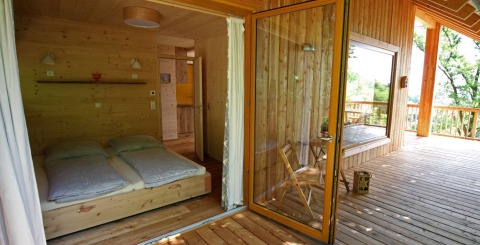 Alloggio glamping Sankt Martin boomhut, accogliente casa sull'albero in legno con letto doppio e ampia terrazza.