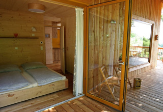 Alloggio glamping Sankt Martin boomhut, accogliente casa sull'albero in legno con letto doppio e ampia terrazza.