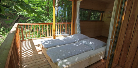 Boomhut met bed op houten terras in het bos, Sankt Martin boomhut - Boomhutten Rijnland-Palts glamping.