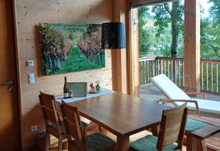 Eethoek met houten meubelen en balkon in de glamping boomhut Sankt Martin, Rijnland-Palts.