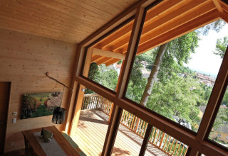 Indvendig udsigt fra Sankt Martin boomhut i Rheinland-Pfalz med store vinduer og naturskøn udsigt.