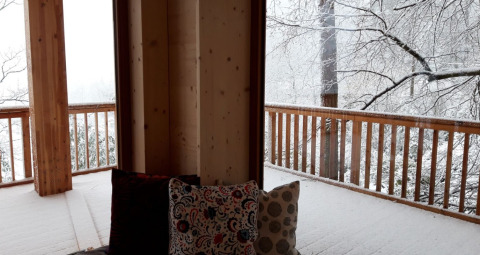 Vista desde Sankt Martin boomhut con cojines en la terraza y árboles cubiertos de nieve en Renania-Palatinado.